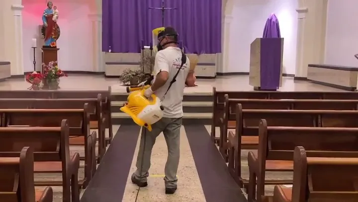Técnico da Gaúcha Dedetizadora aplicando sanitização com equipamento costal em uma igreja de Camboriú